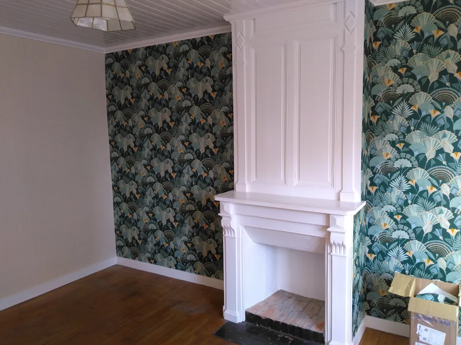 Application d'un papier peint exotique vert foncé et peinture d'une vieille cheminée en blanc