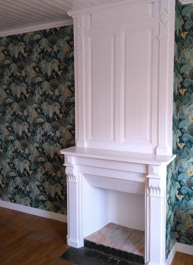 Application d'un papier peint exotique vert foncé et peinture d'une vieille cheminée en blanc